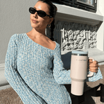 Jente i blå kjole holder en lyserosa tumbler